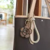 A golden diamond-encrusted flower-shaped keychain with a beige woven leather rope handle ring details Picture